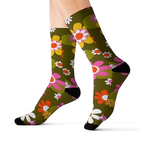May include: A pair of green socks with a colorful floral pattern. The socks feature pink, orange, yellow, and white flowers on a green background.