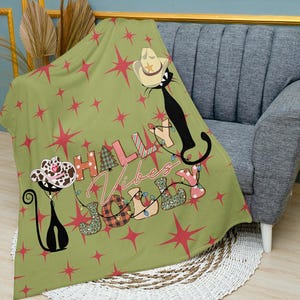 May include: Green throw blanket with a red star pattern and the text "Holly Vibes Jolly" in colorful letters. Two black cats with cowboy hats are featured on the blanket.