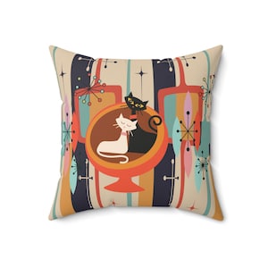 May include: A decorative throw pillow with a retro design featuring two cats in a mid-century modern style globe. The background is a colorful pattern of stripes and abstract shapes.