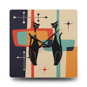 May include: A square clock with a retro mid-century modern design featuring two black cats, geometric shapes in shades of blue, orange, yellow, and red, and a black clock face with hands.