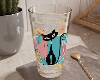 Puede incluir: Un vaso transparente con un diseño de gato retro. El gato negro tiene una cola larga y está sobre un fondo de formas rosas, azules y amarillas. El vaso está lleno de hielo y agua.