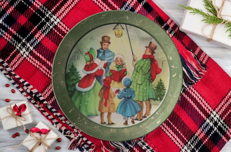 May include: A vintage Christmas plate with a green rim and a festive scene of carolers singing in the snow. The plate features a group of people dressed in winter clothing, holding songbooks and a lantern.
