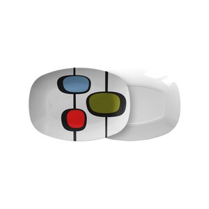 May include: A white oval serving platter with a geometric design featuring three colorful circles in shades of blue, green, and red. The circles are connected by black lines.