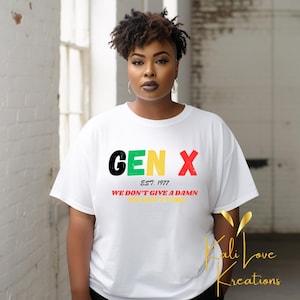 Puede incluir: Camiseta blanca con un diseño gráfico que dice "GEN X EST. 1977 WE DON'T GIVE A DAMN WE DON'T CARE". Las letras son en rojo, verde, amarillo y negro.