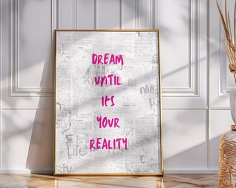 Può includere: Una stampa incorniciata con sfondo bianco e una texture di giornale. Il testo "DREAM UNTIL IT'S YOUR REALITY" è scritto in rosa.