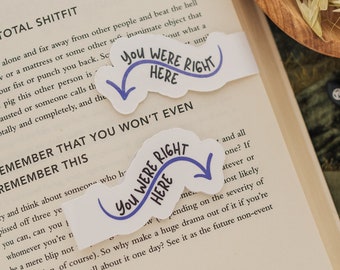 Może przedstawiać: Dwa niebieskie i białe naklejki z tekstem "You were right here" w niebieskim, ozdobnym pismie. Naklejki umieszczono na książce z tekstem "Remember that you won't even remember this" wydrukowanym na stronie.