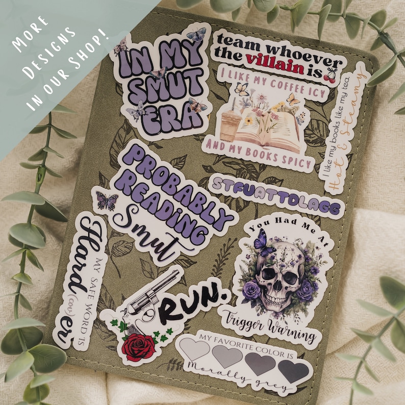 May include: A set of stickers with various designs and phrases, including "In My Smut Era", "Probably Reading Smut", "Harder", "Run", "Team Whoever the Villain Is", "I Like My Coffee Icy and My Books Spicy", "You Had Me At", "Trigger Warning", "My Favorite Color Is Morally Grey".