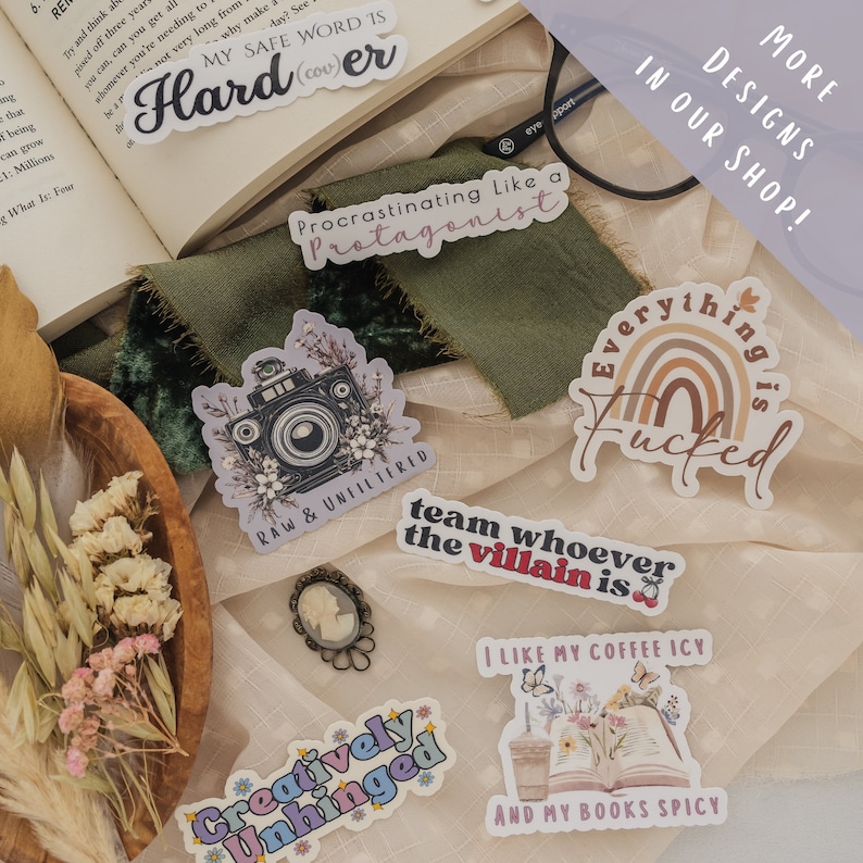 May include: A collection of colorful stickers with various designs and phrases, including "Procrastinating Like a Protagonist", "Team Whoever the Villain Is", "Everything is F*cked", "Creatively Unhinged", "Raw & Unfiltered", and "I Like My Coffee Icy and My Books Spicy".