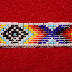 May include: A colorful beaded bracelet with a geometric pattern in shades of red, orange, yellow, blue, white, and black.