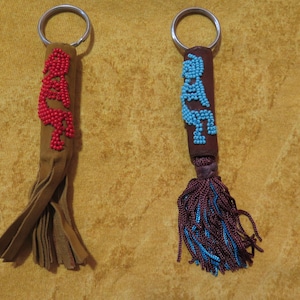 May include: Two beaded keychains with tassels. One keychain is brown with blue beads and the other is brown with red beads.