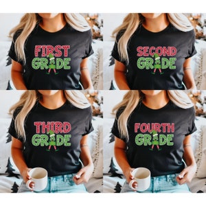 May include: Four black t-shirts with grade level designs. Each shirt has a different grade level: First, Second, Third, and Fourth Grade. The text is in red and green with a cartoon elf illustration.