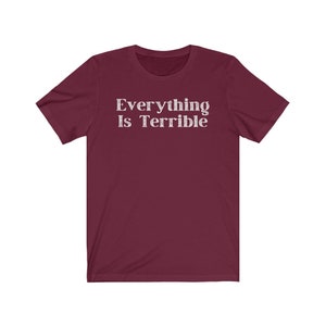 May include: A maroon short-sleeved t-shirt with the text "Everything Is Terrible" printed in white.