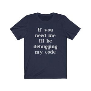 May include: Navy blue t-shirt with white text that reads "If you need me, I'll be debugging my code."