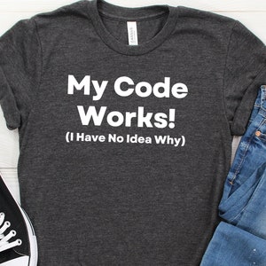 May include: A dark gray t-shirt with white text that reads "My Code Works! (I Have No Idea Why)"