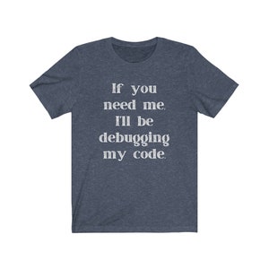 May include: A dark blue t-shirt with the text "If you need me, I'll be debugging my code." printed in white.