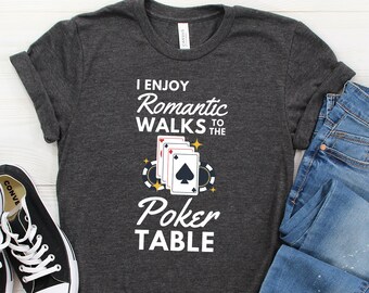 May include: Dark gray t-shirt with the text "I Enjoy Romantic Walks to the Poker Table" and a graphic of playing cards and poker chips. The shirt is made of a soft material and is displayed with blue jeans and a black sneaker.