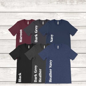 May include: Six t-shirts in different colors, including maroon, dark grey, navy, black, heather grey, and heather navy. Each shirt has a white text label on the side indicating the color.
