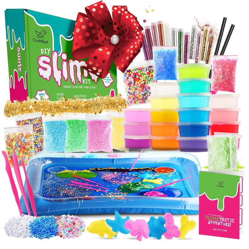 May include: A DIY slime kit with a green and white box, various colors of slime, glitter, and colorful foam beads. Includes a blue inflatable pool, pink tools, and instructions. A large red bow with white polka dots is at the top.