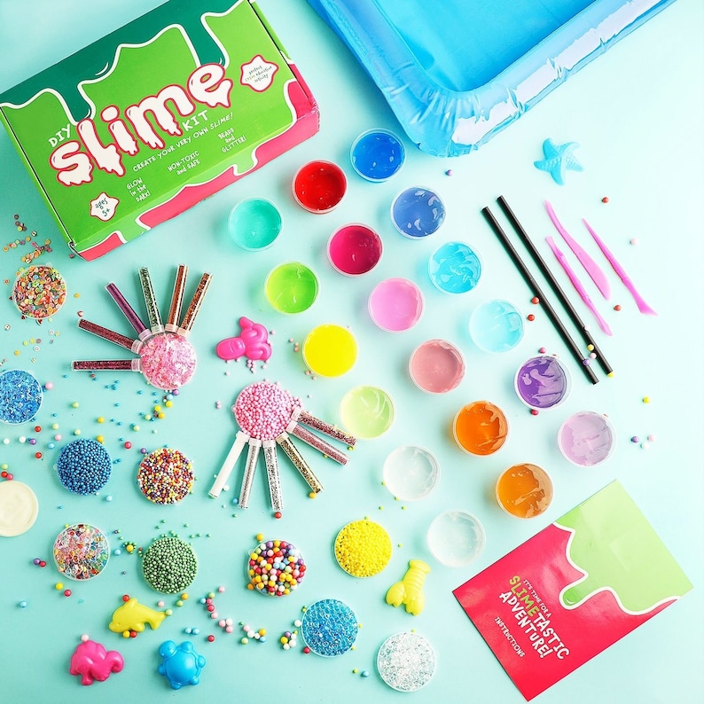 May include: A DIY slime kit with various colorful slime ingredients, including glitter, beads, and small plastic molds. The kit includes a green and red box with the words "DIY Slime Kit" and an inflatable blue pool.