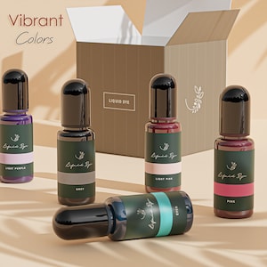May include: Five small bottles of liquid dye in various colors, including light purple, grey, light pink, cyan, and pink. The bottles are labeled "Liquid Dye" and have a black cap. The bottles are arranged in a row on a light brown surface. The text "Vibrant Colors" is visible in the top left corner of the image.