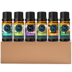 May include: Set of six 10 ml amber glass bottles with black caps, containing essential oils. The bottles are labeled with the names of the oils: Eucalyptus, Tea Tree, Lavender, Lemongrass, Orange, and Peppermint. The bottles are arranged in a row on a brown cardboard box.