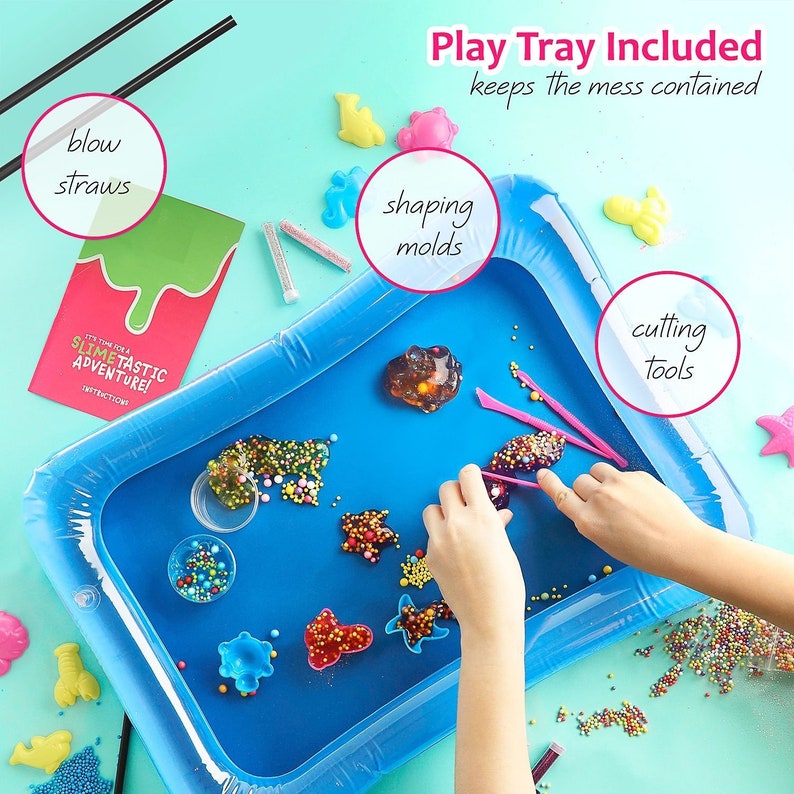 May include: A blue inflatable play tray filled with colorful slime, shaping molds, and cutting tools. The set includes blow straws and a booklet that reads "It's Time For A Slimetastic Adventure!" The text "Play Tray Included keeps the mess contained" is also visible.