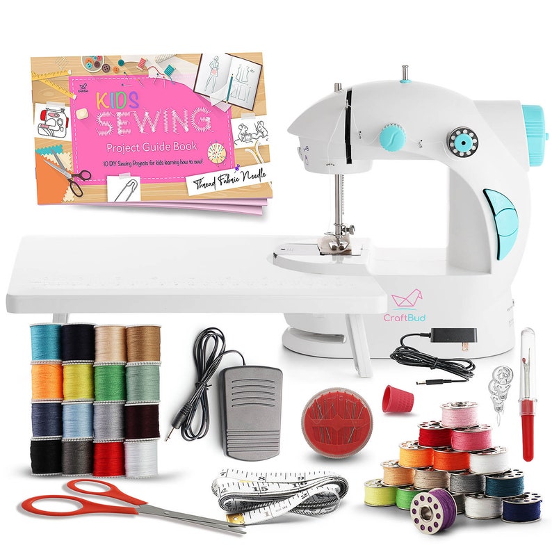 May include: A white sewing machine with a blue and white foot pedal, a white table, a book titled "Kids Sewing Project Guide Book", a spool of thread, a needle, a pair of scissors, a measuring tape, and a variety of colored thread spools.