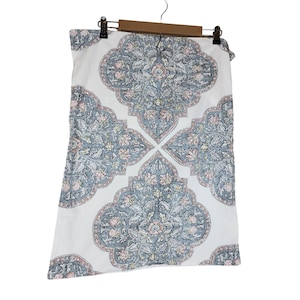 May include: White pillowcase with a large, symmetrical floral pattern in shades of gray, pink, and green. The pillowcase is hanging on a wooden hanger against a white background. The design is reminiscent of a traditional textile.