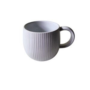 May include: A white ceramic mug with a ribbed exterior and a rounded handle. The mug has a simple, modern design and is suitable for coffee, tea, or other beverages. The mug is approximately 4 inches tall.