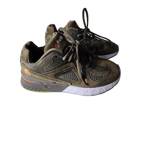 May include: A pair of olive green athletic shoes with white soles and gray accents. The shoes have mesh and suede panels, orange and red details, and white laces. The brand name is visible on the side of the shoe.