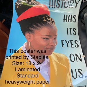 May include: A poster with a woman wearing a red headband and a yellow jacket. The poster says "HISTORY HAS ITS EYES ON US." and "Amanda Gorman". The poster is 18 inches by 24 inches and printed on laminated heavyweight paper.