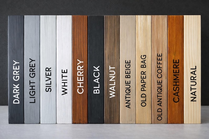 May include: A collection of twelve rectangular wooden planks arranged vertically, each featuring a distinct finish. The labels printed on the planks are Dark Grey, Light Grey, Silver, White, Cherry, Black, Walnut, Antique Beige, Old Paper Bag, Old Antique Coffee, Cashmere, and Natural.