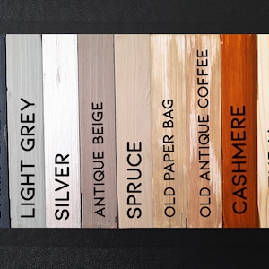May include: A collection of wooden color swatches labeled with paint names. Colors range from dark grey to natural, including light grey, silver, antique beige, spruce, old paper bag, old antique coffee, and cashmere.