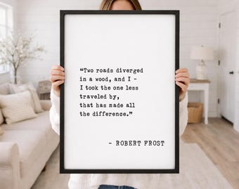 May include: A framed print with a black border, displaying a quote by Robert Frost in a classic font. The quote reads, "Two roads diverged in a wood, and I - I took the one less traveled by, that has made all the difference."