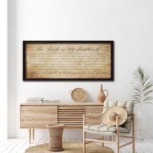 May include: A framed print with a rustic wood background and a black frame. The print features a bible verse, "The Lord is my shepherd:" I shall not want He makes me to lie down in green pastures. He leads me beside the still waters He restores my soul He leads me in the paths of righteousness for His names sake, Yea. Though I walk through the valley of the shadow of death. I will fear no evil for You are with me Your rod and Your staff, they comfort me You prepare a table before me in the presence of my enemies You anoint my head with oil my cup runs over Surely goodness and mercy shall follow me all the days of my life And I will dwell in the house of the Lord forever