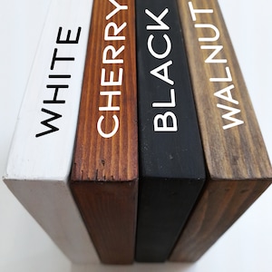 May include: Four wooden blocks in white, cherry, black, and walnut colors. Each block has a different color and the name of the color is printed in white on the side of each block. The blocks are arranged side by side.