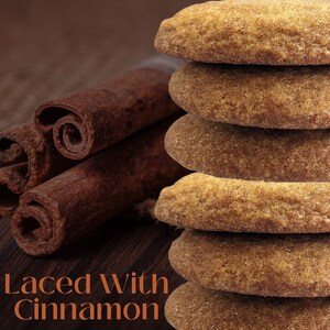 May include: A stack of six brown cinnamon cookies with a close-up of cinnamon sticks in the background. The text "Laced With Cinnamon" is at the bottom of the image.