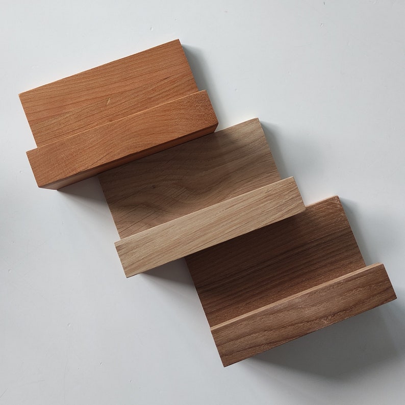 May include: Three wooden shelves, each with a different wood grain pattern. The top shelf is a light brown, the middle shelf is a medium brown, and the bottom shelf is a dark brown.