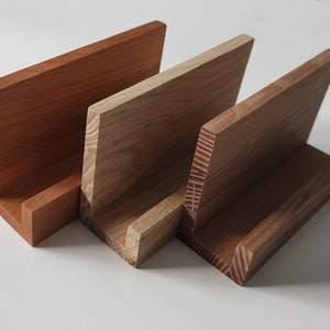 May include: Three wooden display stands, one is a light brown, one is a medium brown, and one is a dark brown. The stands are all made of wood with a natural finish.