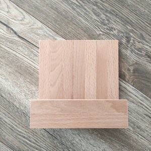 May include: A wooden stand with a rectangular top and a shelf underneath. The stand is made of light brown wood and has a natural finish.