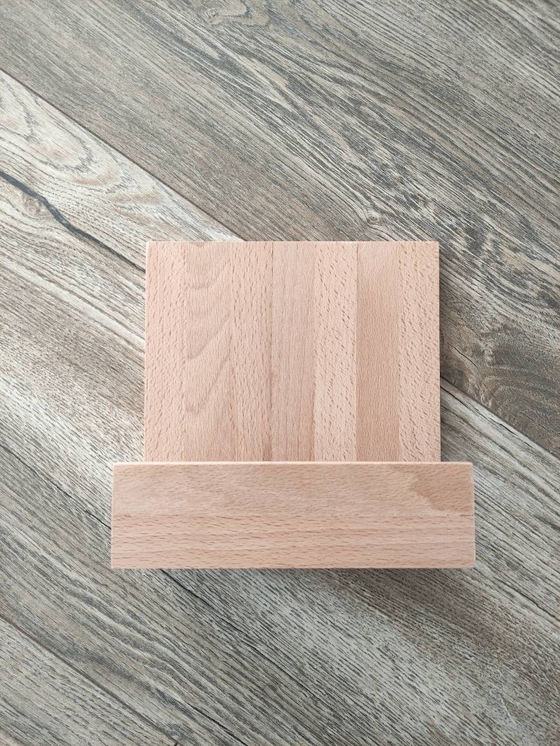 May include: A wooden stand with a rectangular top and a shelf underneath. The stand is made of light brown wood and has a natural finish.