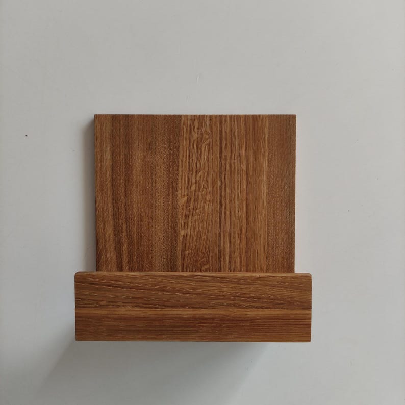 May include: A wooden wall shelf with a rectangular top and a lower shelf. The shelf is made of light brown wood with a wood grain pattern.