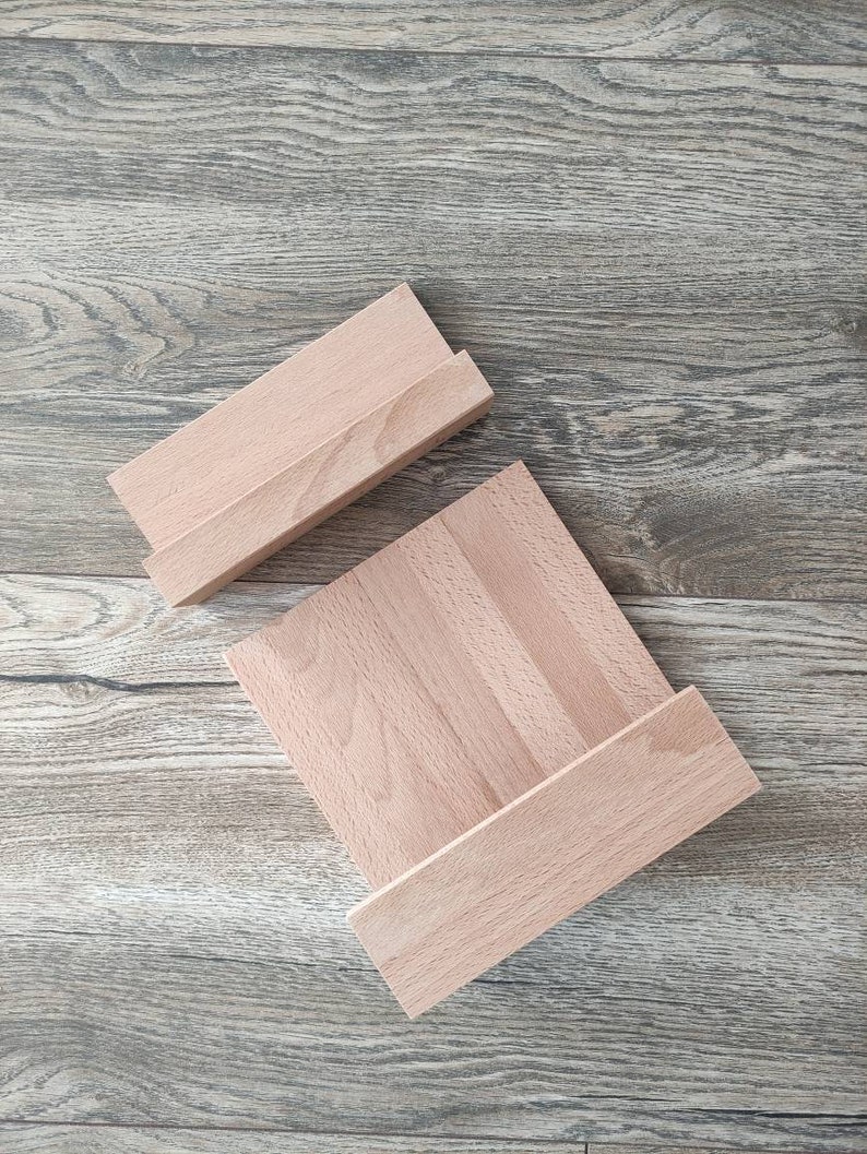 May include: Two wooden shelves, one stacked on top of the other, with a natural wood finish. The shelves are made of solid wood and have a simple, rectangular shape.