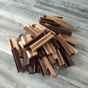 K&ouml;nnte beinhalten: Ein Stapel aus Holzst&auml;bchen in verschiedenen Braunt&ouml;nen und hellem Holz. Die St&auml;bchen sind in einem zuf&auml;lligen Muster angeordnet, einige &uuml;berlappen sich, andere stehen aufrecht.