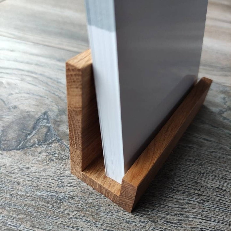 May include: A wooden stand for displaying books or other items. The stand is made of natural wood and has a simple, elegant design.