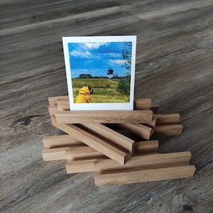 K&ouml;nnte beinhalten: Ein Holz-Bilderrahmen mit einem Foto eines Hundes in einem gelben Regenmantel, der auf einen Leuchtturm in der Ferne blickt. Der Rahmen besteht aus mehreren &uuml;bereinander gestapelten Holzst&uuml;cken.