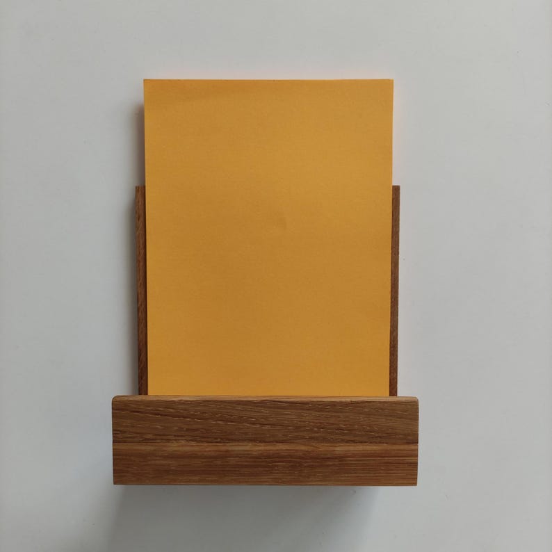 May include: A wooden wall-mounted shelf with a yellow piece of paper inside. The shelf has a natural wood finish.