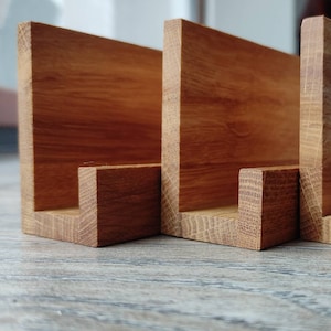 May include: Three wooden shelves with a natural finish, each with a U-shaped opening. The shelves are arranged in a row and are made of a light brown wood.