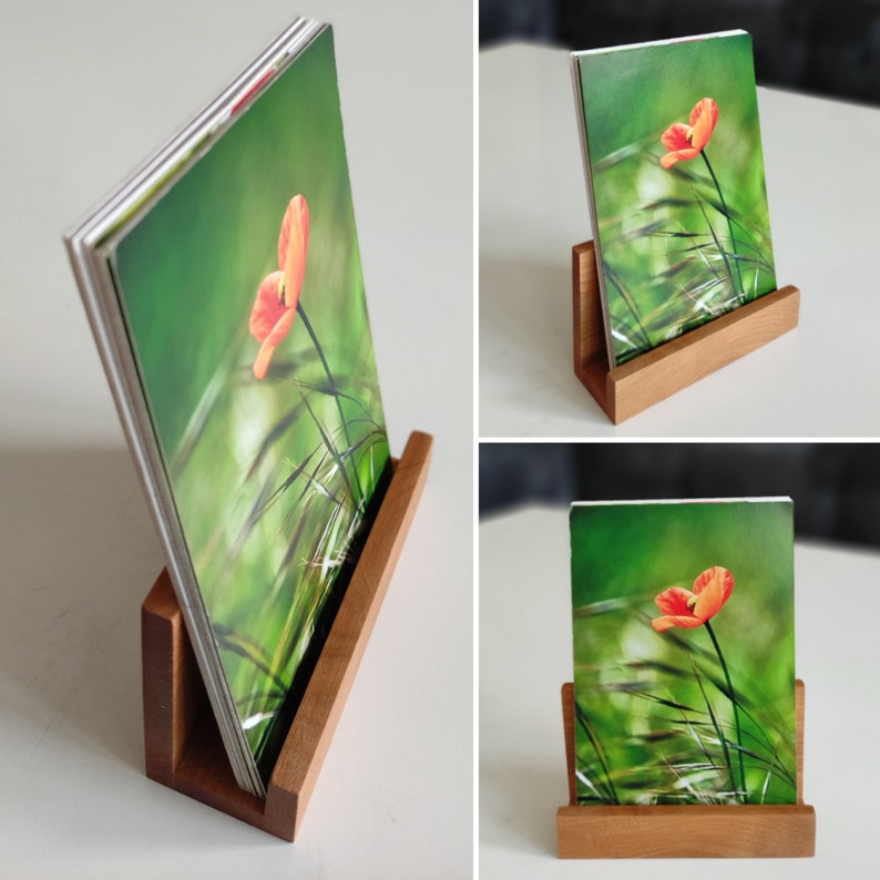 May include: A wooden photo stand with a single photo of a poppy flower in a field of green grass. The photo is held in place by a wooden frame.