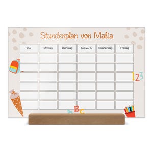Puede incluir: Un tablero de horario escolar con el texto "Stundenplan von Malia" en naranja. El tablero tiene una cuadrícula para los días de la semana y los horarios. Ilustraciones coloridas de una mochila, un cono escolar, lápices y números decoran el tablero. Está soportado por una base de madera.